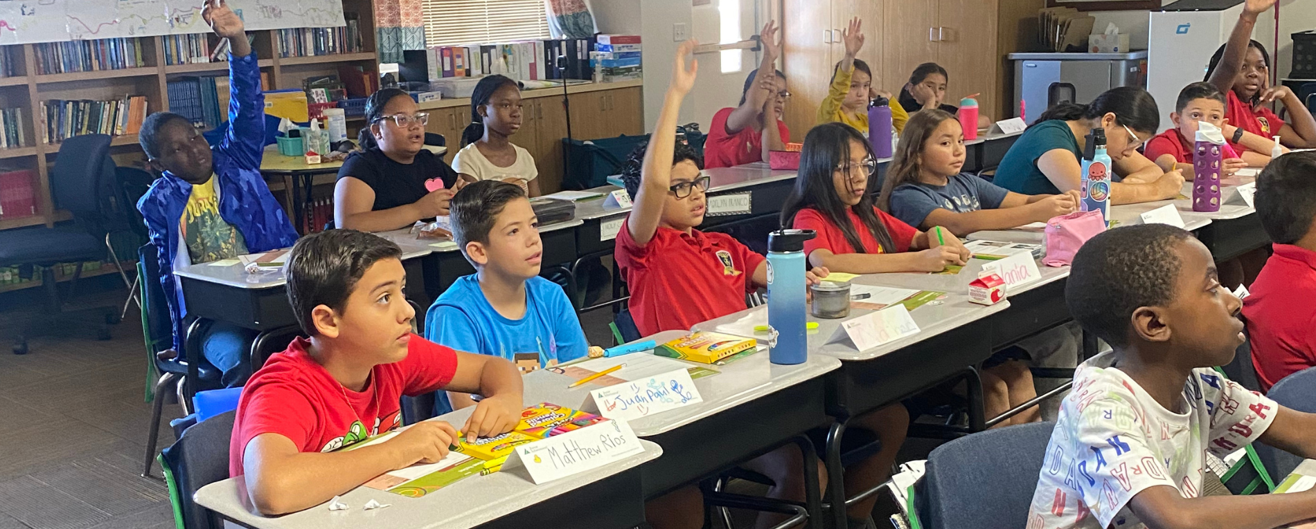 Students raising hands in classroom